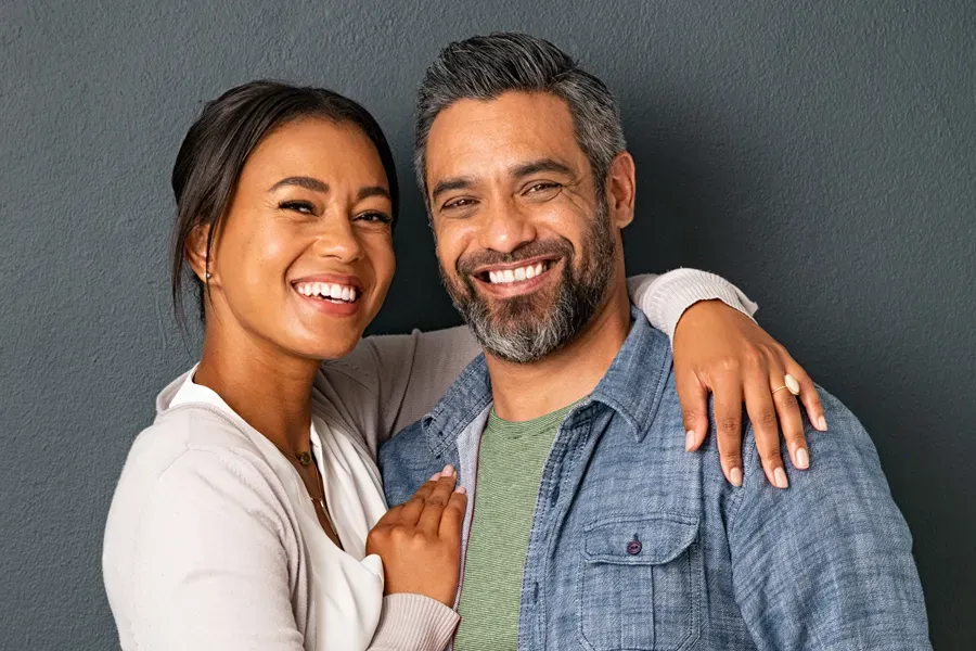 Bioidentical-Hormone-Therapy-Doctor A middle-aged couple with their arms around each other standing against a gray background and smiling, happy with the bioidentical hormone therapy they received from Better Life Carolinas of Charlotte in Charlotte Metro.