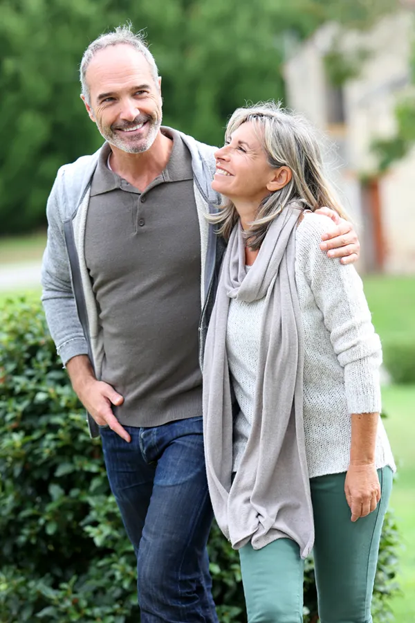 Bioidentical-Hormone-Therapy-Treatment A mature couple in gray toned clothes and jeans walk happily outside, happy with their successful bioidentical hormone treatments from Better Life Carolinas of Charlotte in Charlotte Metro.