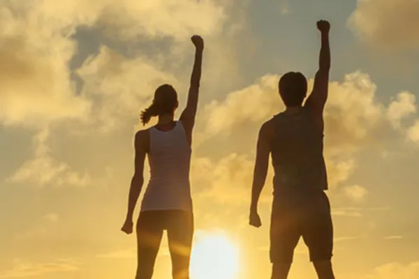 Ipamorelin-Peptide-Clinic A couple raise their right arms in the air in triumph, framed by the sunrise. Get Ipamorelin peptide treatment from Better Life Carolinas of Charlotte in Charlotte Metro.