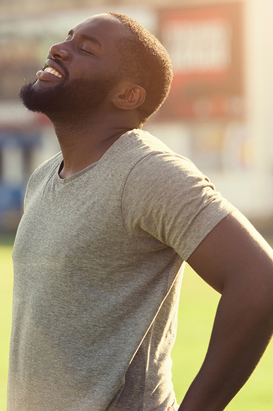 Lean-Muscle-and-Recovery-Treatment A black man in a gray t-shirt and smiles, looking up with closed eyes after a satisfying workout. Get treatment for lean muscle loss and recovery from Better Life Carolinas of Charlotte in Charlotte Metro.