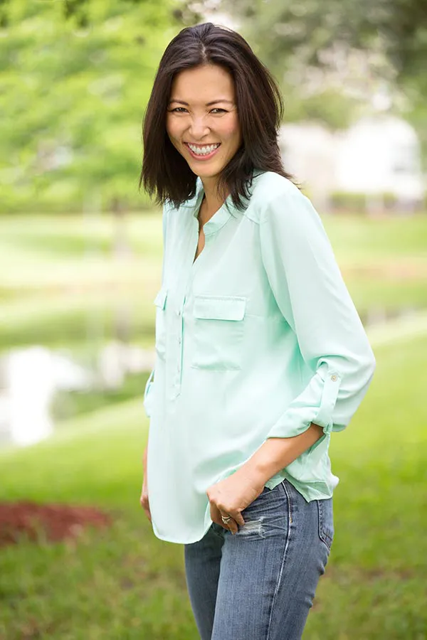 Perimenopause-Treatment A middle-aged brunette woman in a light green button-up shirt stands outside smiling, happy with her perimenopause treatment from Better Life Carolinas of Charlotte in Charlotte Metro.