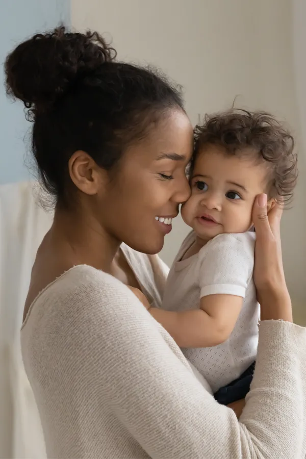 Postpartum-Hormone-Imbalance-Treatment A black woman happily touches her forehead to her infant's head. Get treatment for postpartum hormone imbalance from Better Life Carolinas of Charlotte in Charlotte Metro.